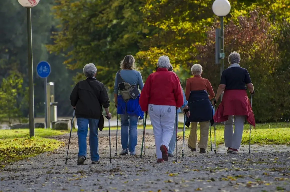 Grupa osób starszych na spacerze z kijkami, wspierająca rehabilitację po bajpasach.