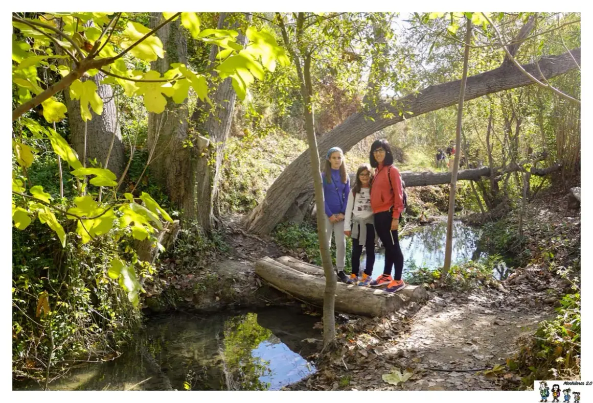 Familia posa en la ruta del agua Sella, disfrutando del sendero boscoso y el arroyo.