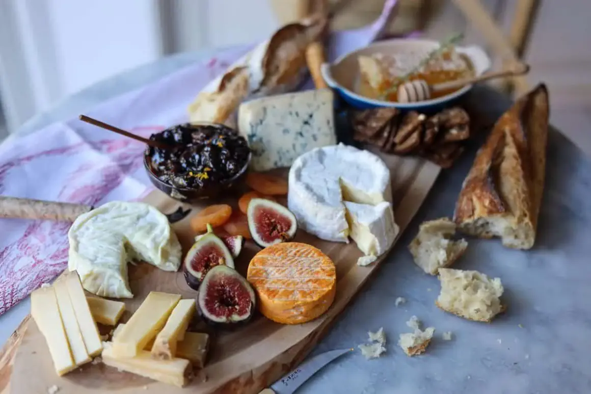 Un plateau gourmand pour explorer l'univers du fromage : brie, bleu, chèvre, pain, figues, abricots secs et miel.