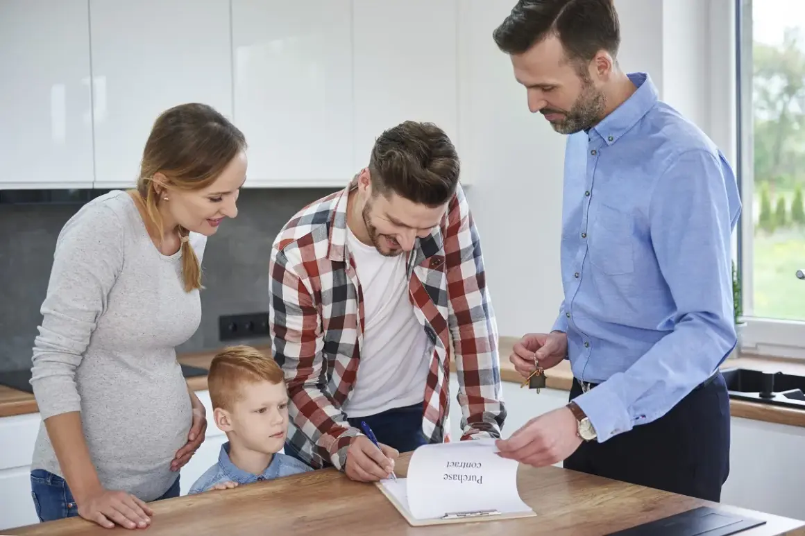 Familia firma contrato de compraventa. El agente inmobiliario les explica que es legal pedir aval para un alquiler.