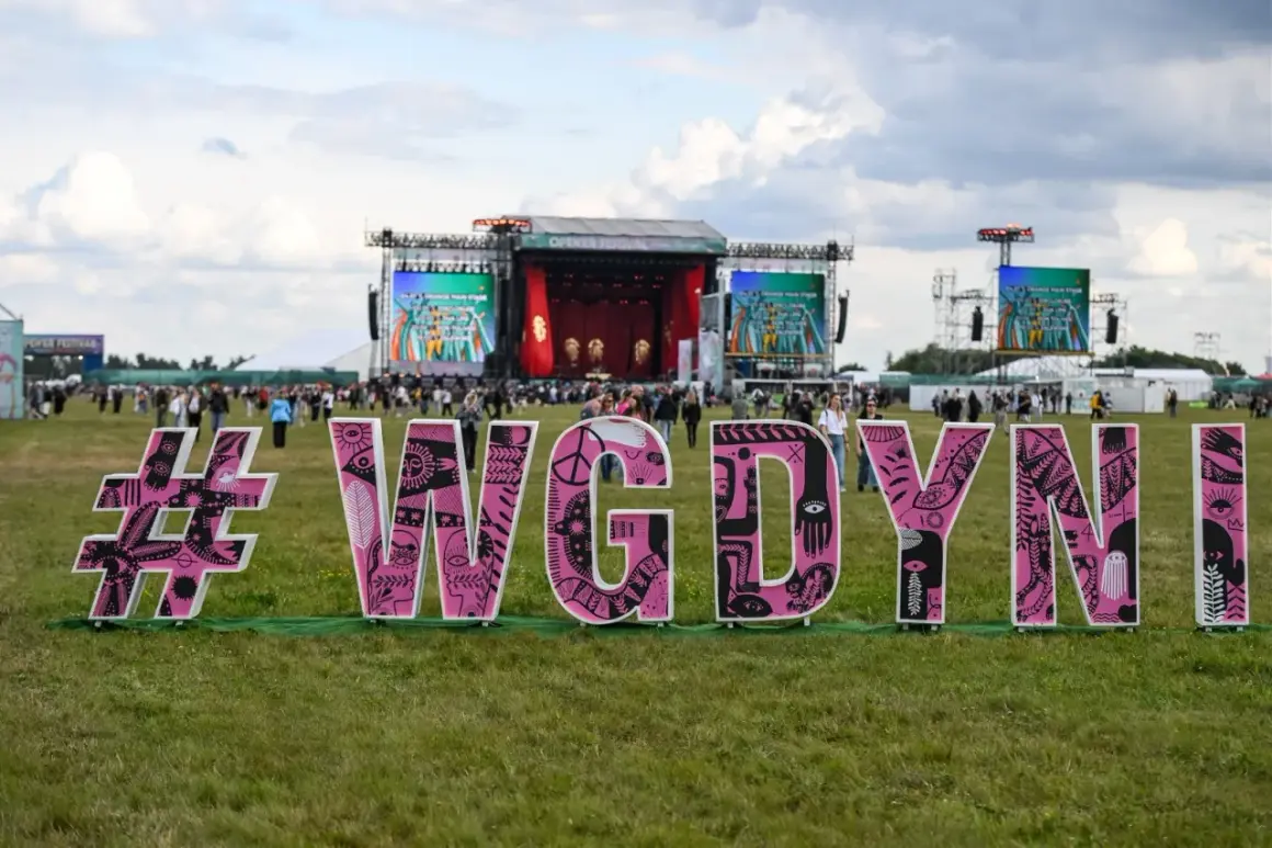 Różowe litery #WGDYNI na trawie przed sceną festiwalową Open'er.