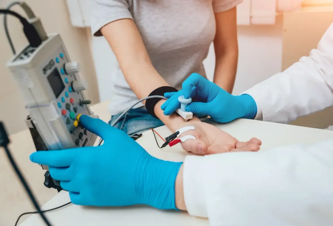 Lekarz w niebieskich rękawiczkach wykonuje próbę tężyczkową, przykładając elektrodę do przedramienia pacjentki.