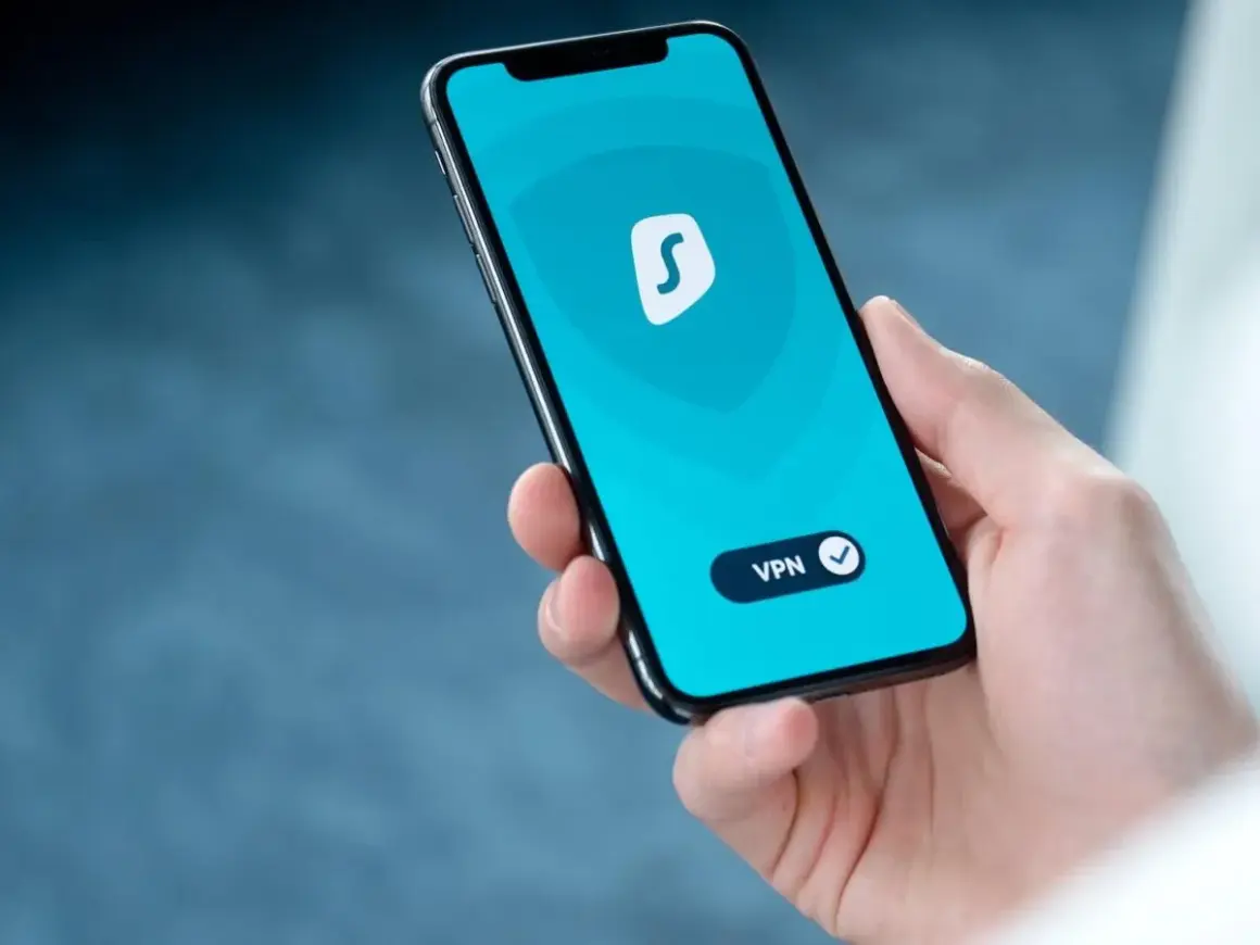 Dłoń trzyma smartfon z włączoną aplikacją VPN. To pokazuje, co to jest VPN w telefonie i jak chroni Twoją prywatność online.