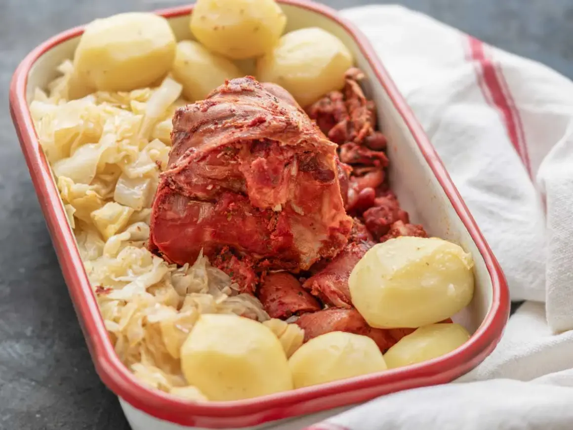 Un plato de botillo, con repollo, patatas y trozos de carne roja.