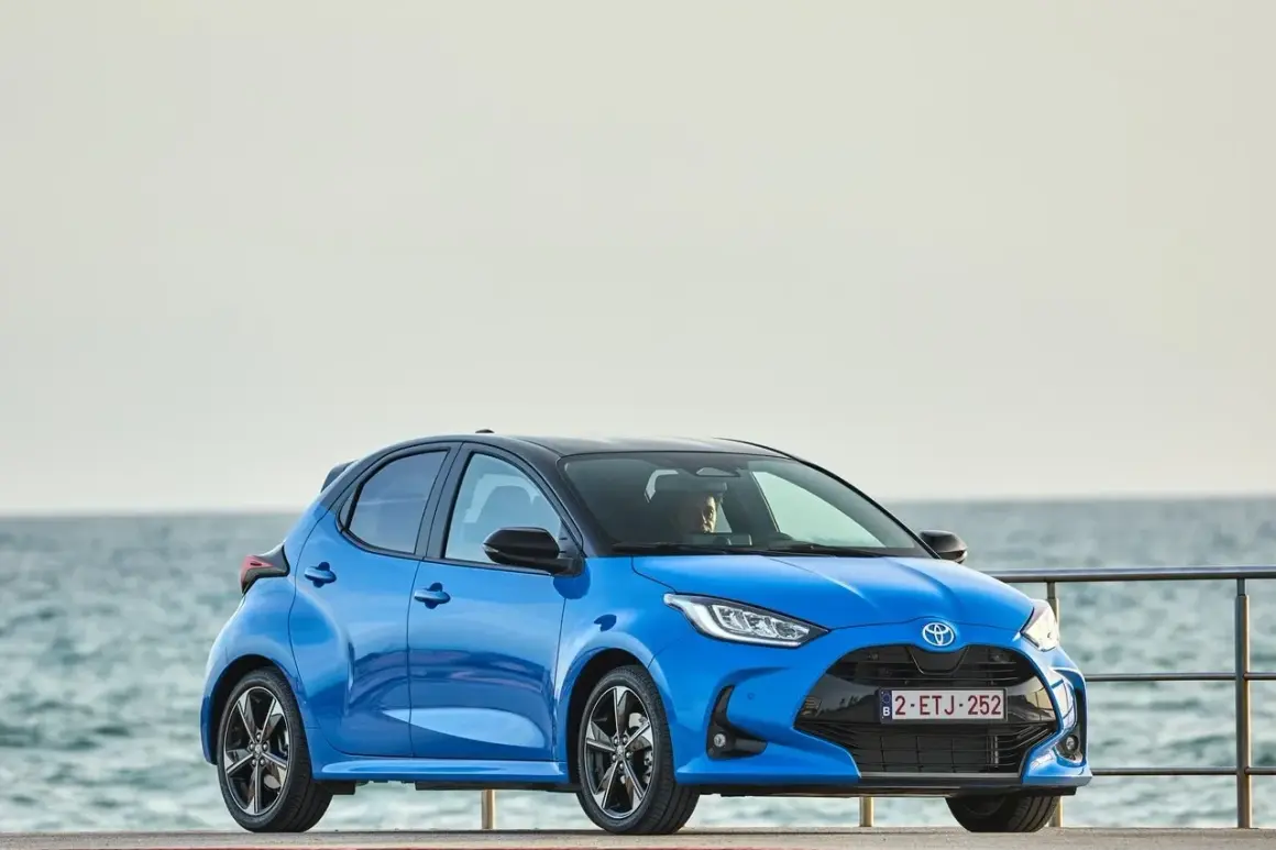 Niebieski segment a, Toyota Yaris, stoi przy morzu.