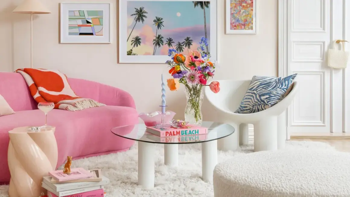 Ein Wohnzimmer im **danish pastel** Stil mit pinkem Sofa, bunten Blumen und Kunstwerken.