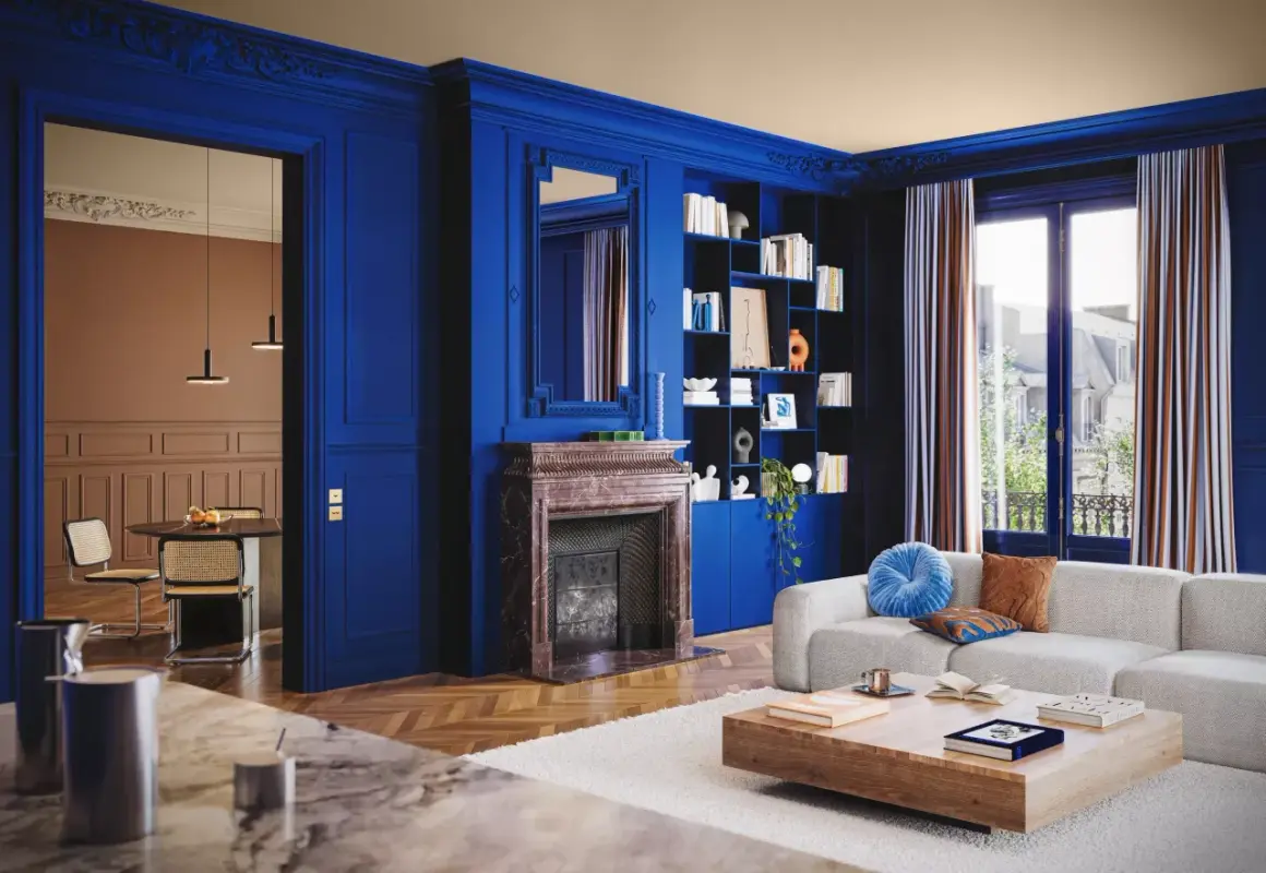 Un soggiorno elegante con pareti blu intenso, camino in marmo, libreria e divano bianco. Un'altra stanza con tavolo e sedie è visibile attraverso un'apertura.