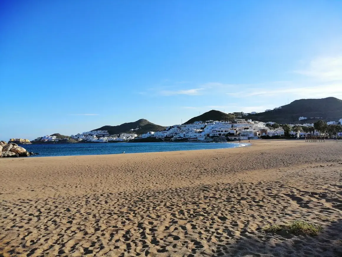 Playa de San José, con casas blancas en la ladera y el mar azul. ¡Qué carallo de vista!