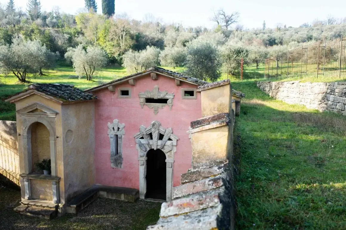Un edificio rosa con decorazioni barocche, immerso in un uliveto. Sembra la fonte della fata morgana, un luogo incantato.