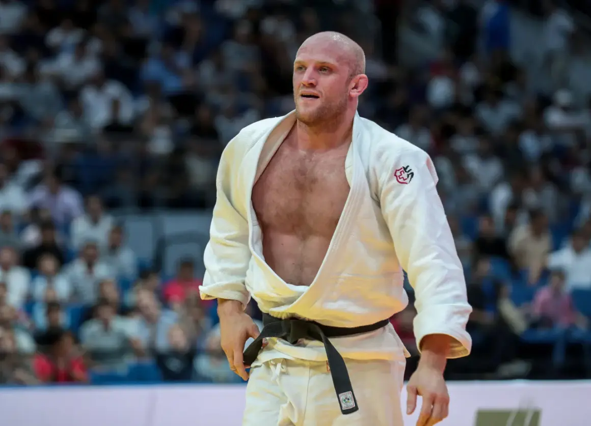 Marcus Nyman, en svensk judoka, står på mattan i sin vita dräkt med svart bälte. Publiken syns i bakgrunden.