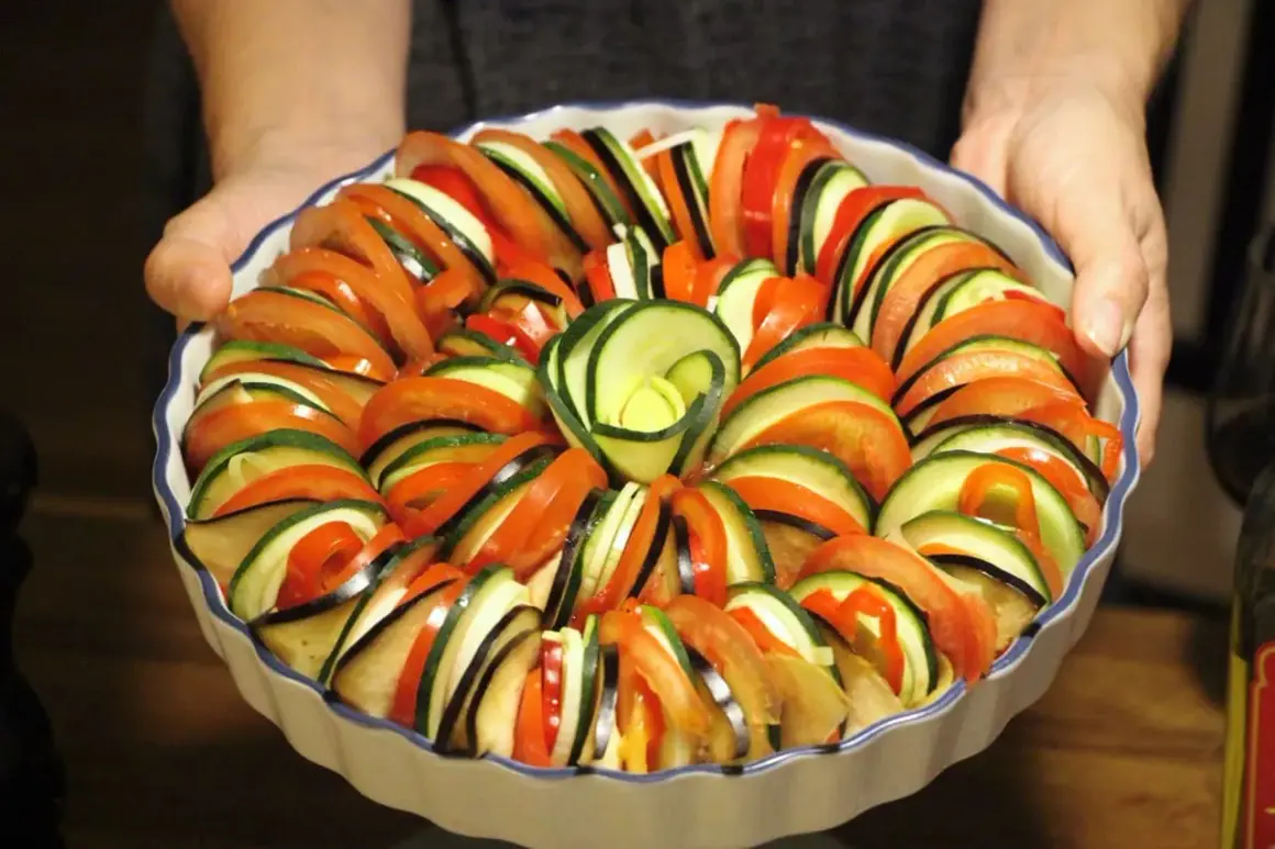 Vacker ratatouille i ugnsform, redo för ugnen. Ett perfekt ratatouille recept med skivade grönsaker som tomat, zucchini och aubergine.
