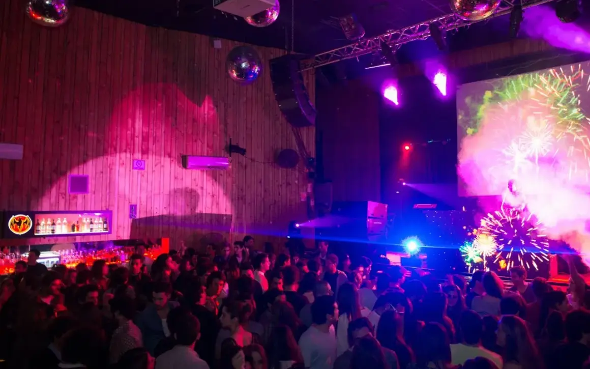 Festa al Macarena Club Barcelona, con luci stroboscopiche, DJ e fuochi d'artificio sullo schermo.