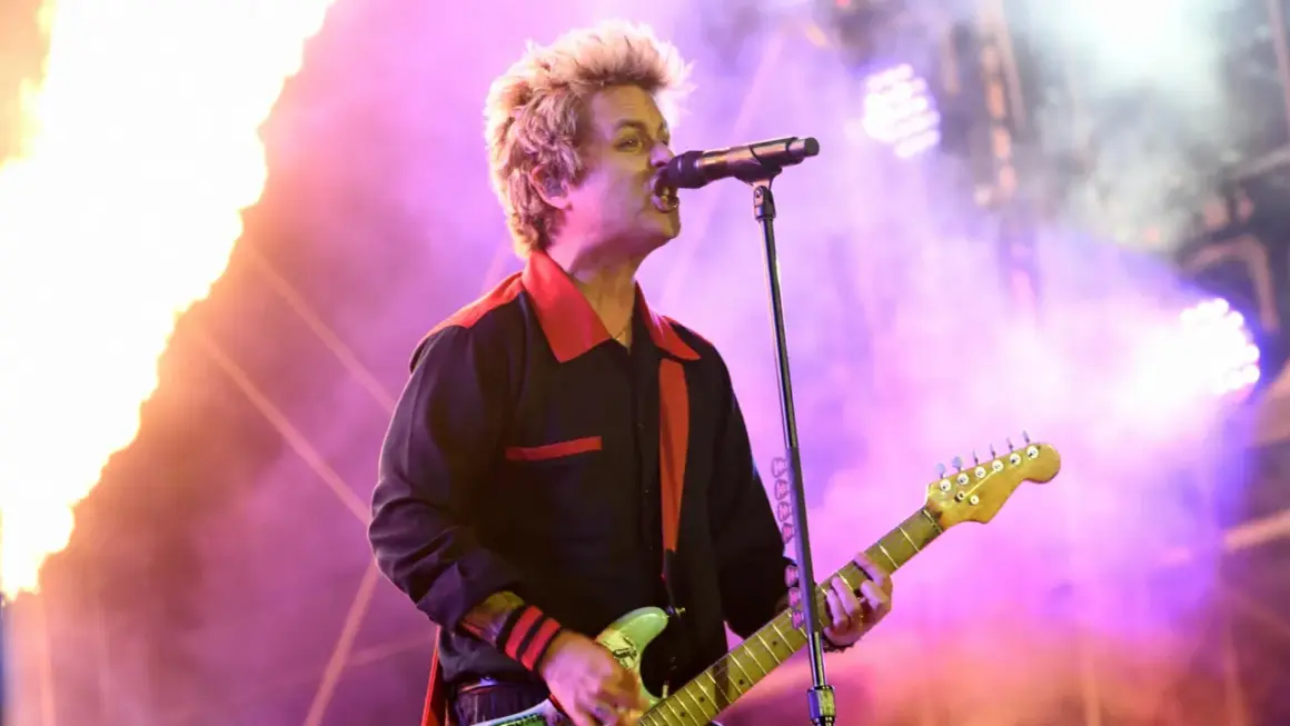 Billie Joe Armstrong von Green Day rockt die Bühne beim Rock am Ring Festival, umgeben von Flammen und lila Licht.