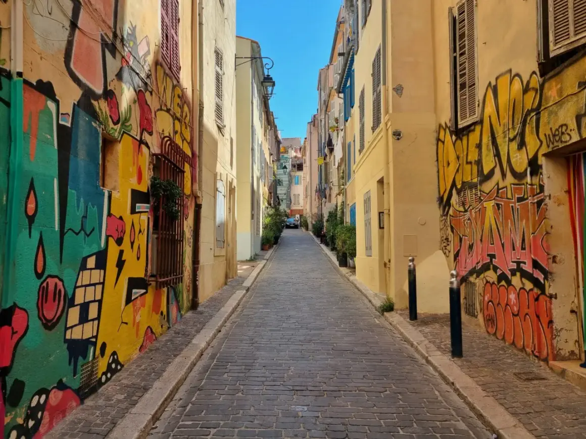 Kolorowa uliczka z brukowaną nawierzchnią, ozdobiona dynamicznym street art graffiti na ścianach budynków.