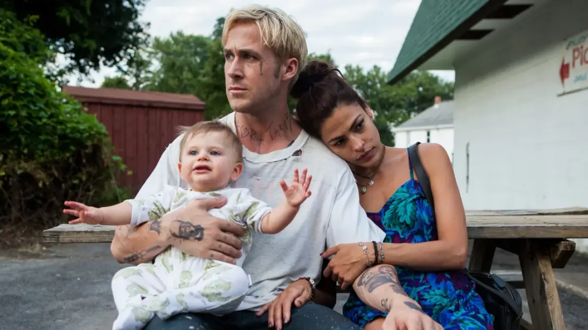 Ryan Gosling barn i famnen, med Eva Mendes vid sin sida. En stund av familjefrid trots omgivningen.
