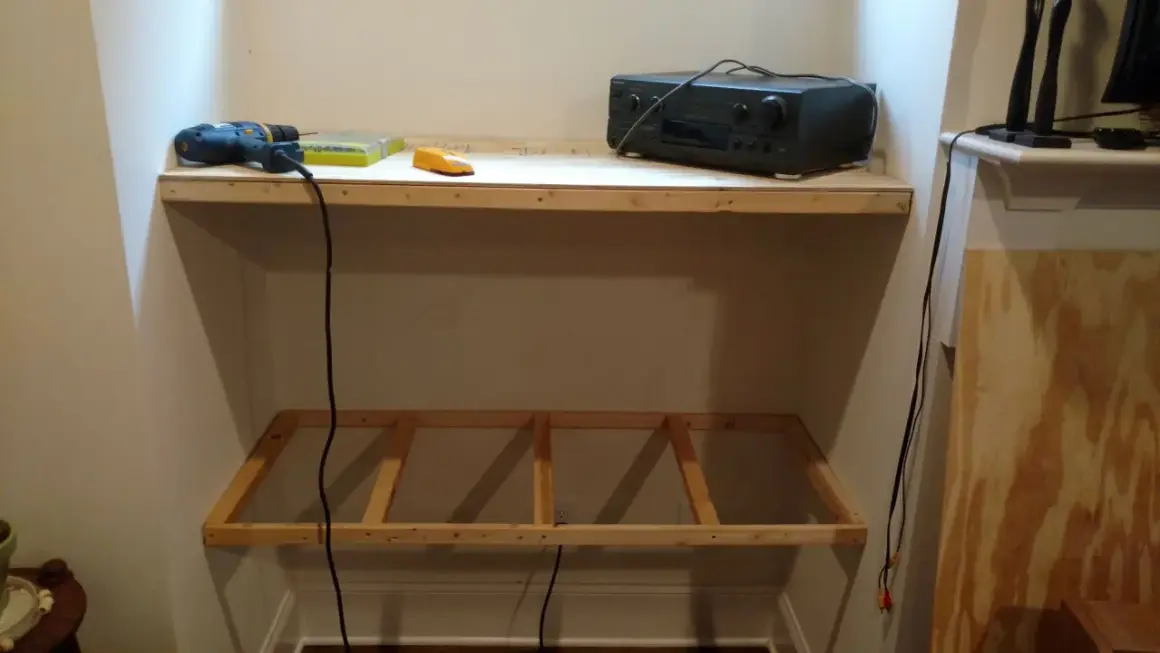DIY project: a drill, level, and audio receiver sit on a wooden shelf, with a frame for another shelf below, showing how to hang shelves.