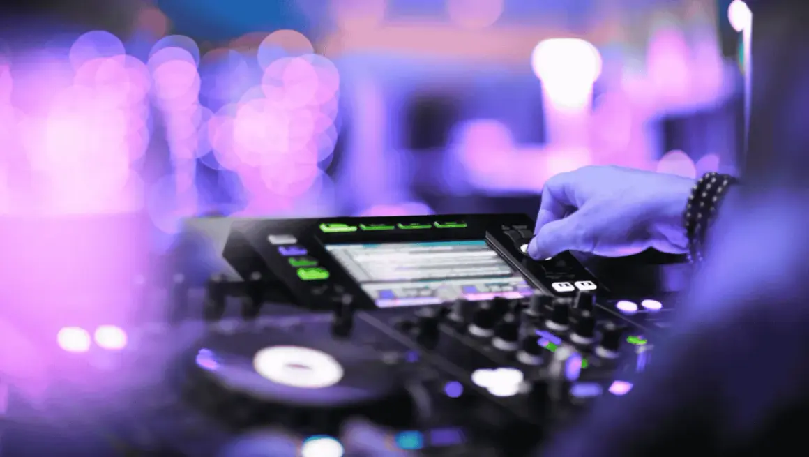 Mano che mixa su console DJ, luci viola e rosa sfocate creano l'atmosfera perfetta per la techno house music.
