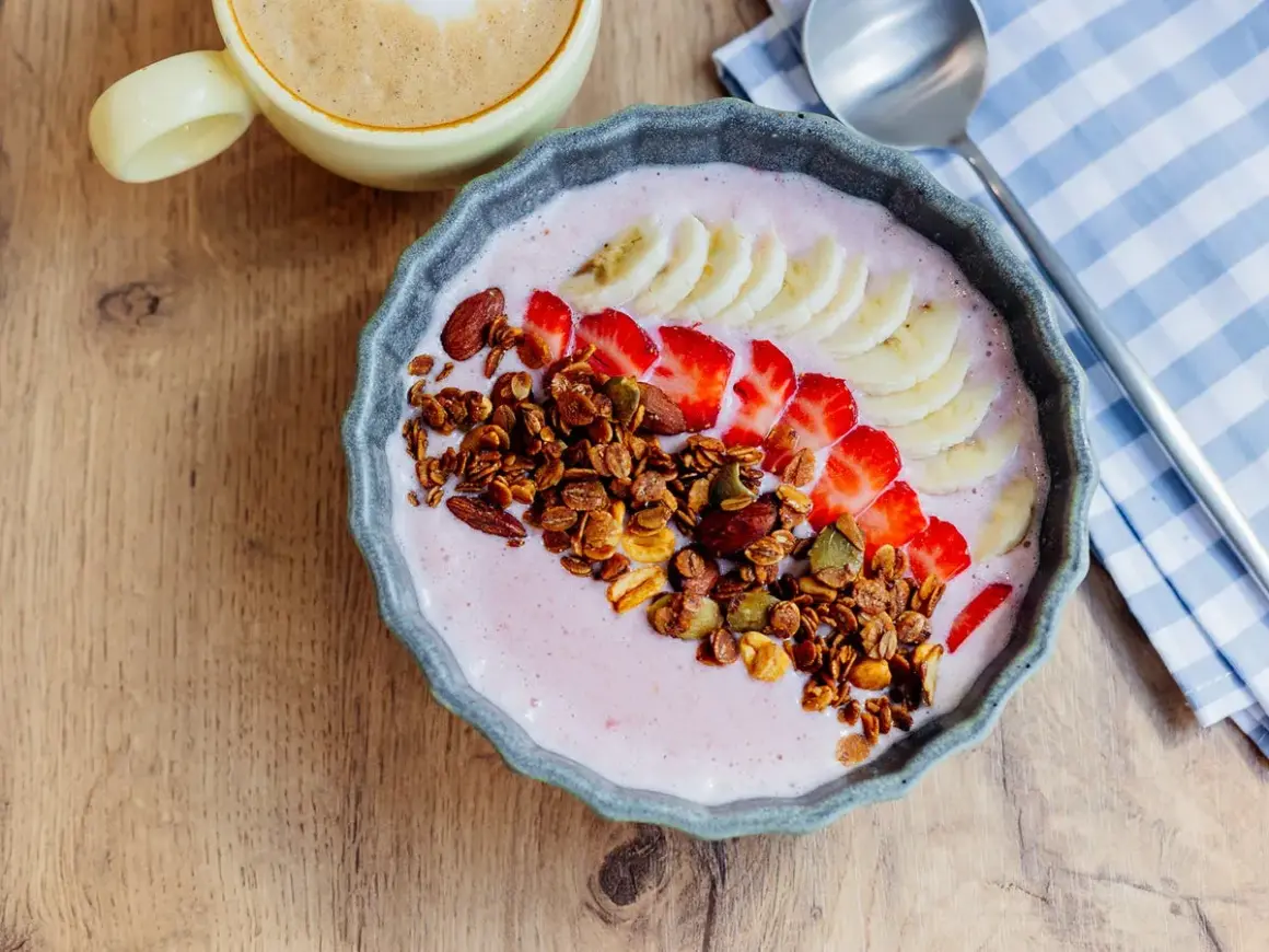 Un delicioso tazón de batido de bayas de acai con fresas, plátano, granola y almendras.