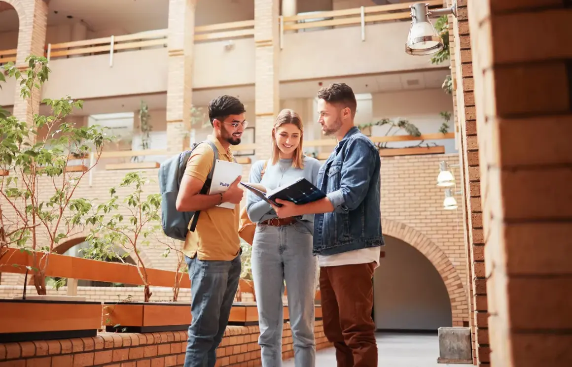 Drei Studierende planen ihren Auslandssemester Master in einem modernen Gebäude.
