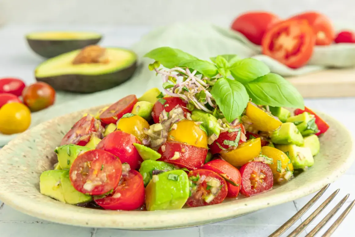 Frischer **avocado tomaten salat** mit Basilikum und Sprossen, garniert mit roten und gelben Kirschtomaten.