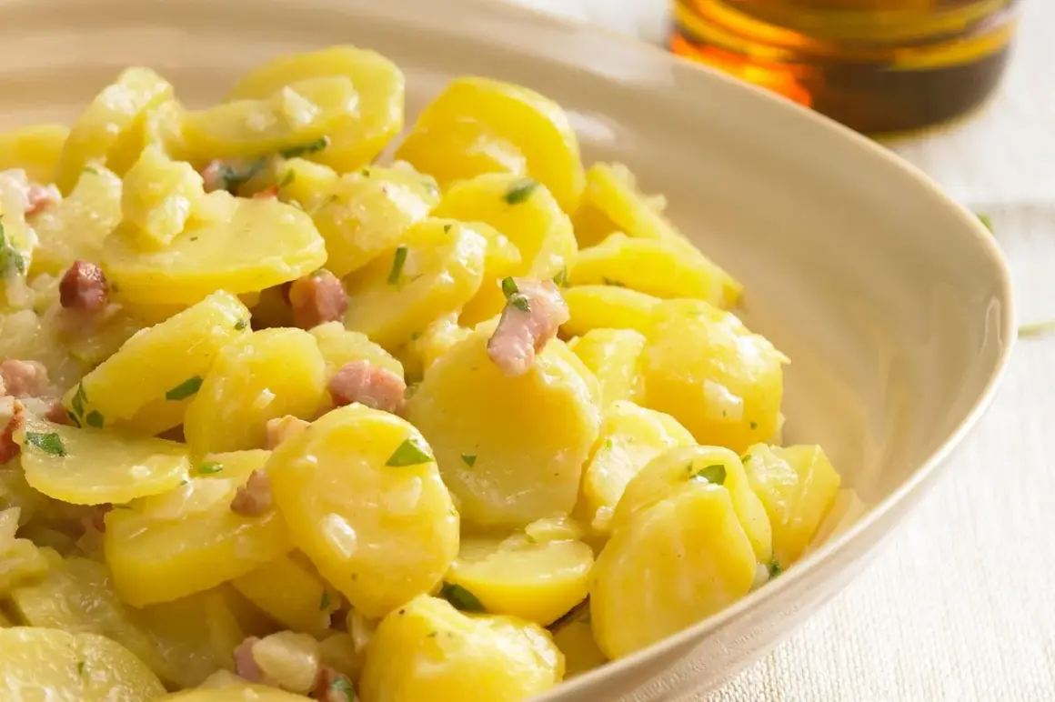 Ein cremiger Kartoffelsalat mit Speck und Petersilie, serviert in einer hellen Schüssel.