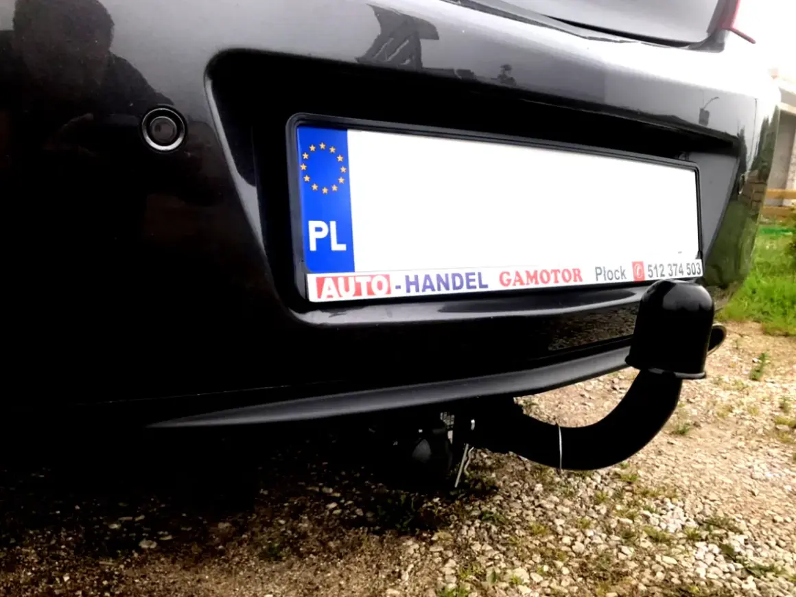 Widok z tyłu samochodu Opel Insignia z zamontowanym modułem haka. Widoczna tablica rejestracyjna i czujnik parkowania.