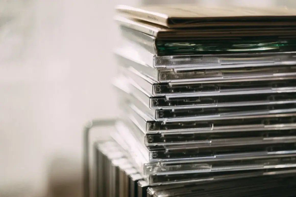 Stos przezroczystych pudełek z płytami CD, idealny do przechowywania nowości płytowych.