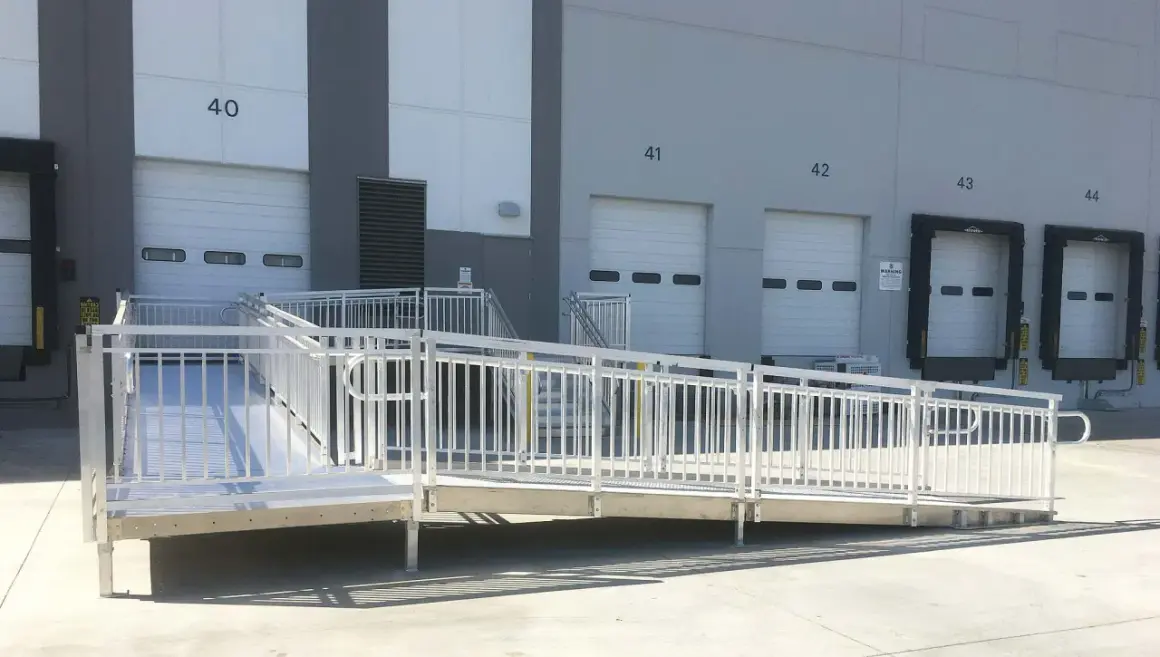 A modular wheelchair ramp system is installed outside a warehouse, providing accessibility to loading docks. This shows how to build a wheelchair ramp for easy access.