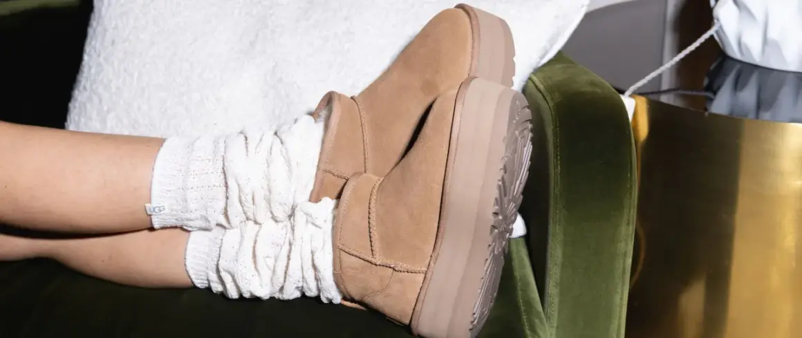 Pieds chaussés de bottes en daim UGG, avec des chaussettes blanches torsadées. Un aperçu de l'entretien chaussure daim.