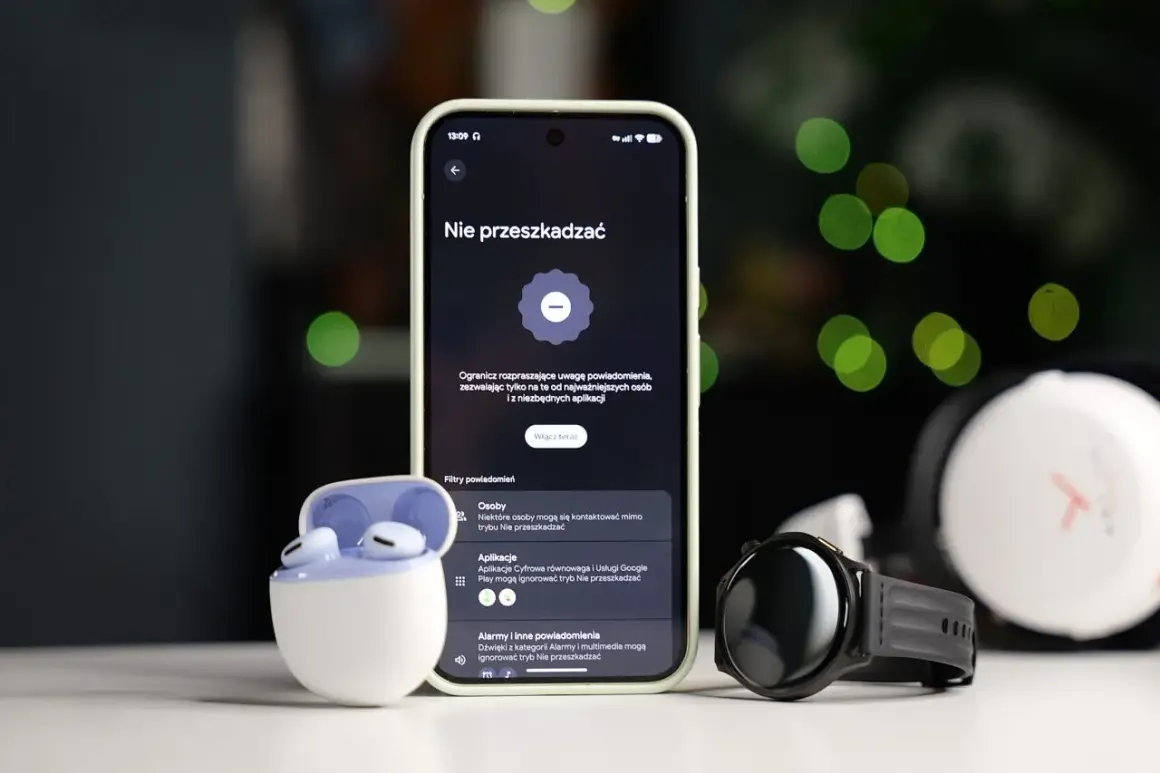 Smartfon z włączonym trybem nie przeszkadzać Samsung, obok słuchawki i smartwatch.