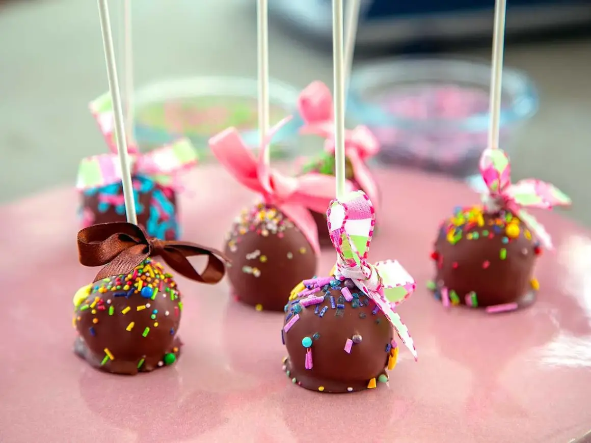 Chokladöverdragna cake pops med färgglada strössel och fina band. Perfekta för ett kalas!