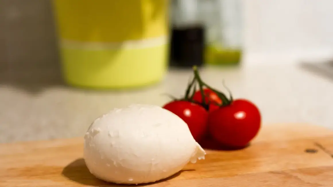 Frische Mozzarella und Kirschtomaten auf einem Holzbrett. Perfekt für eine leichte Mahlzeit während der Schwangerschaft.