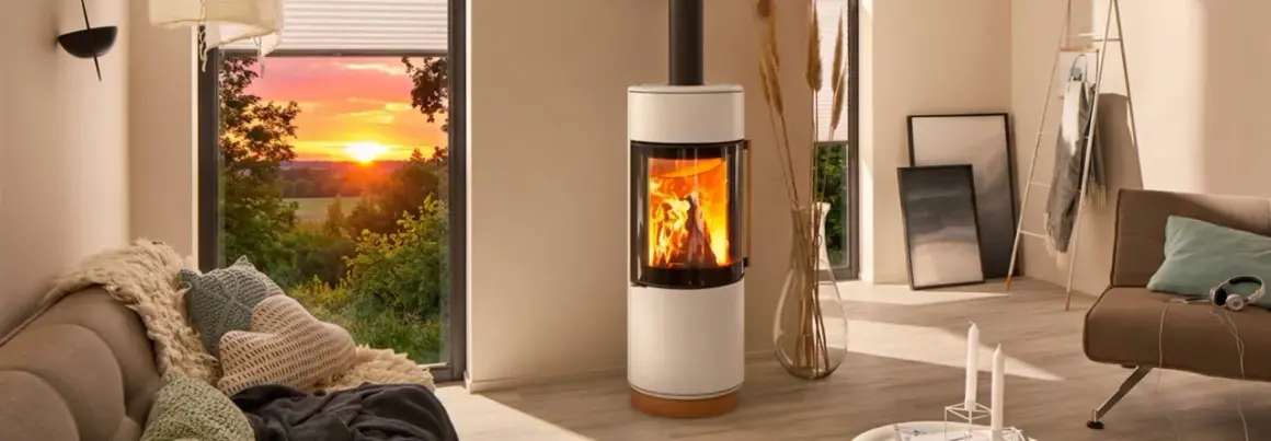 Gemütliches Wohnzimmer mit brennendem Kamin, der die Frage aufwirft: darf man im Sommer den Kamin anmachen? Sonnenuntergang draußen.