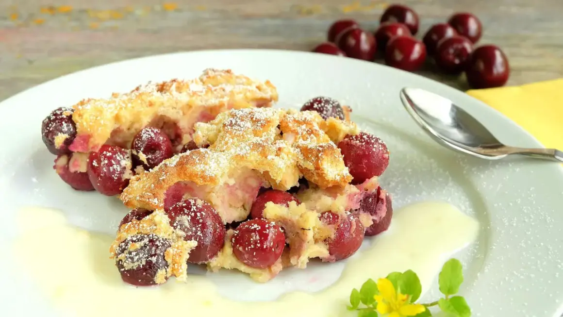 Zwei Portionen Kirschenmichel, ein köstliches Dessert, serviert mit Vanillesauce und bestäubt mit Puderzucker. Ein perfektes Kirschenmichel Rezept.