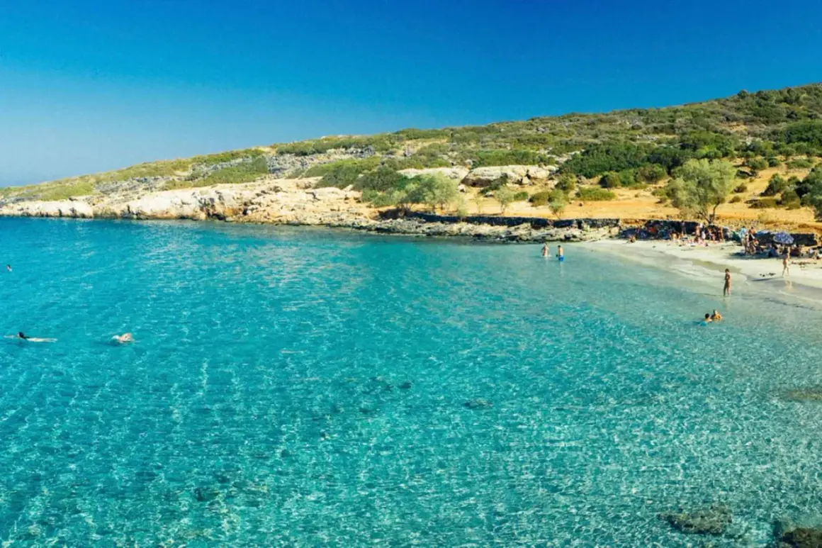 En solig strand med turkost vatten och människor som badar. En perfekt dag att se på Kreta.