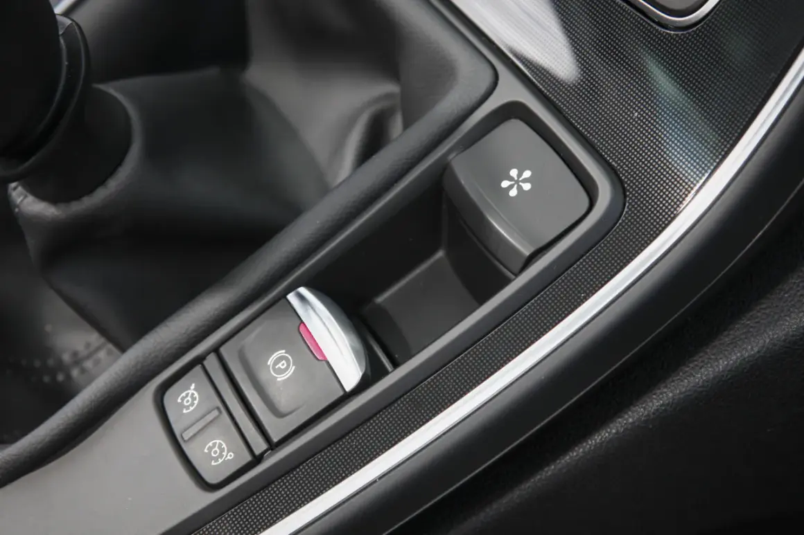 Bouton de frein à main électronique et autres commandes dans une voiture. Le frein à main ne serre plus, prix de la réparation à considérer.