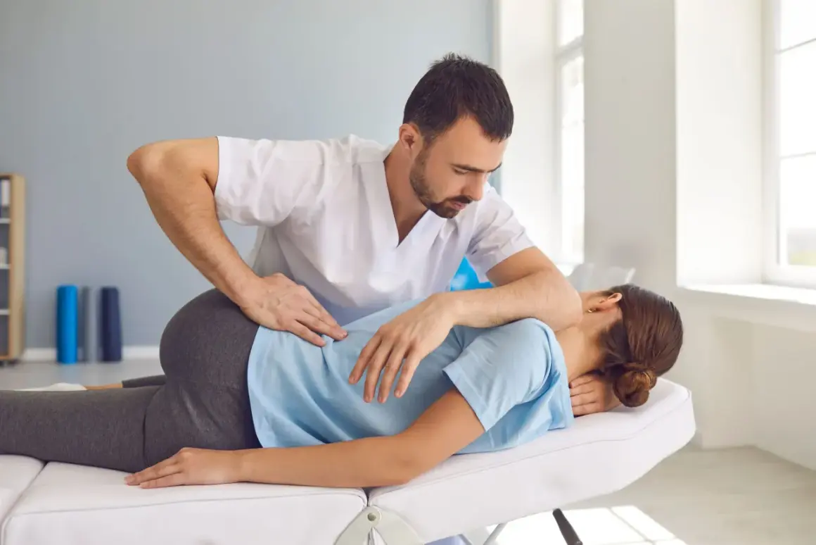 Fizjoterapeuta wykonuje terapię manualną, uciskając plecy pacjentki. To pokazuje, na czym polega terapia manualna – na pracy z ciałem.