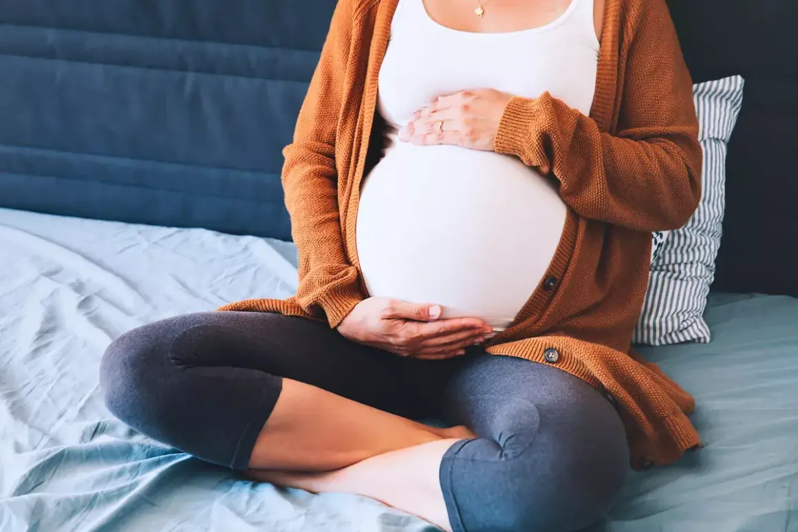 Mujer embarazada sentada, con las manos sobre su vientre. Ejercicios para el embarazo y alivio de la pubalgia.