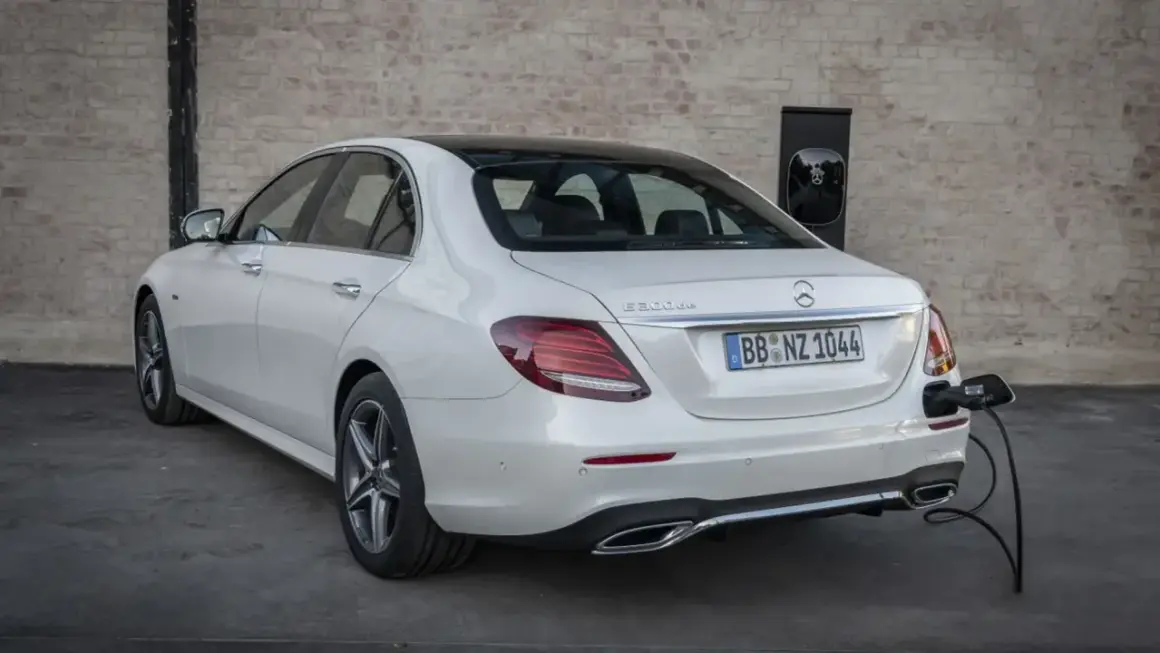 Un Mercedes 300de blanco, con el distintivo "E 300de", está enchufado a un cargador eléctrico.