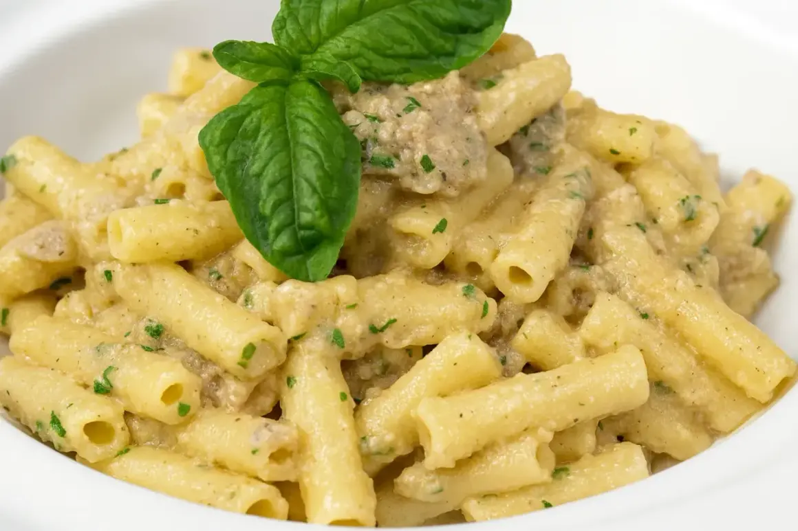 Piatto di pasta con melanzane in bianco, condita con una cremosa salsa e guarnita con basilico fresco.