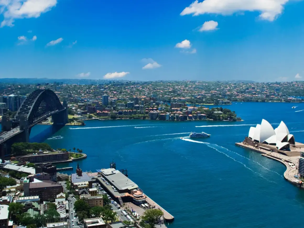 Widok na Zatokę Sydney z Operą i mostem Harbour Bridge. To właśnie Sydney, gdzie błękitna woda lśni w słońcu.