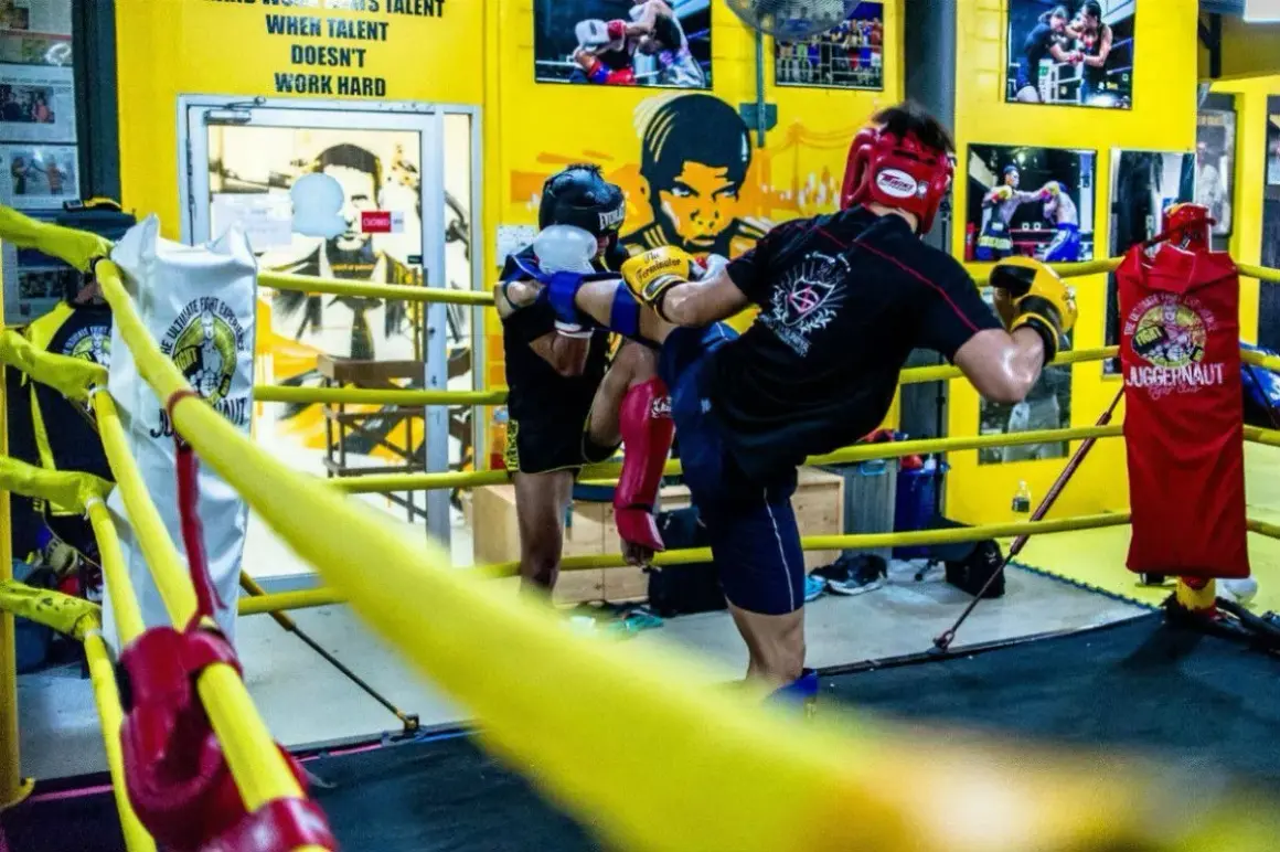 Two fighters practice kicks in a boxing ring, showcasing the intense benefits of sparring for skill development and conditioning.