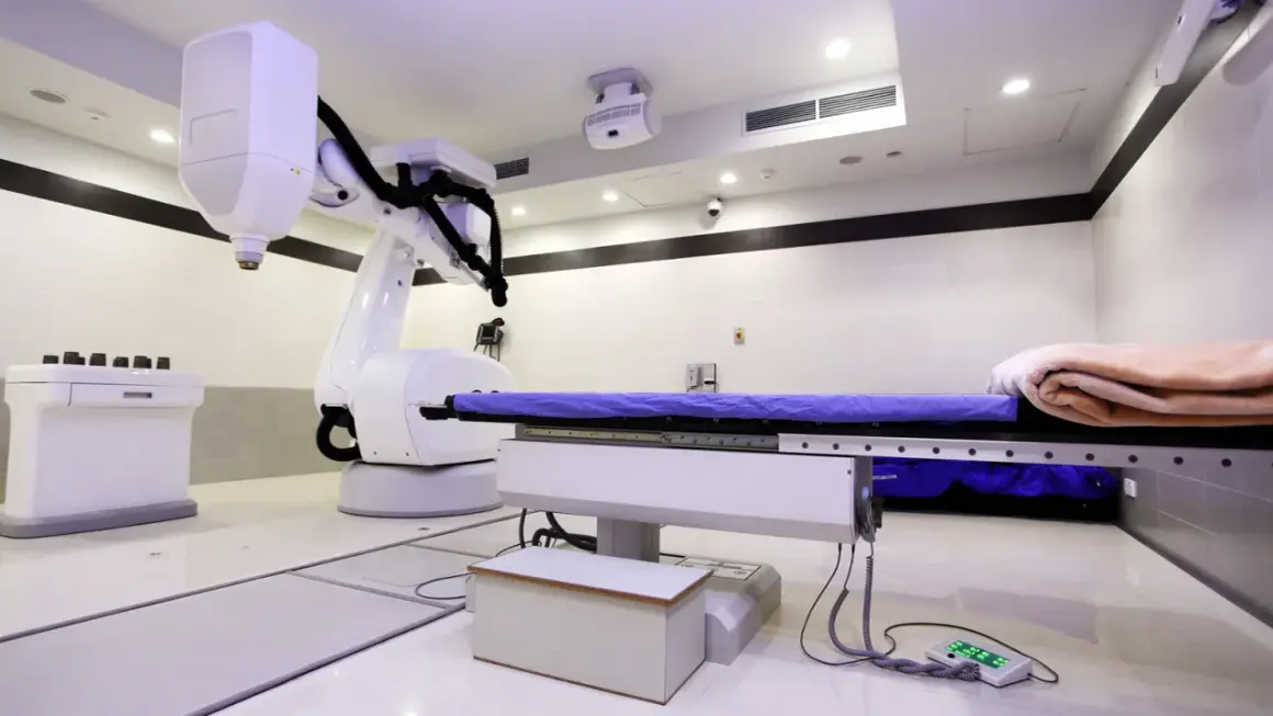 Ein CyberKnife-Behandlungsraum mit Roboterarm und Liege. Mögliche CyberKnife Nachteile sind die Kosten und die Notwendigkeit präziser Planung.