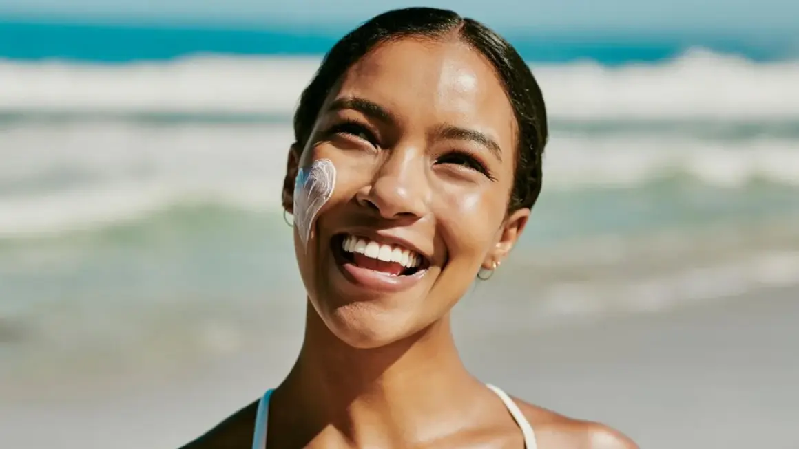 Strahlendes Lächeln am Strand, Sonnencreme schützt vor Hautalterung.