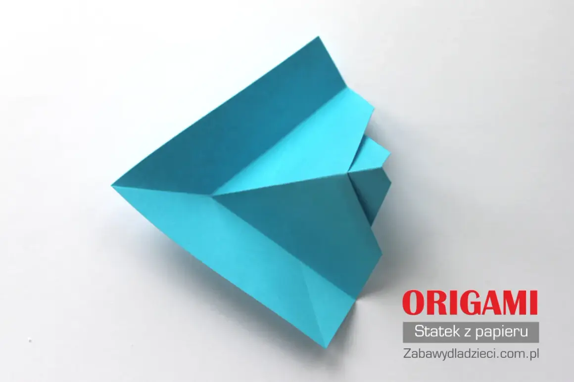 Niebieski statek z papieru złożony techniką origami na białym tle.