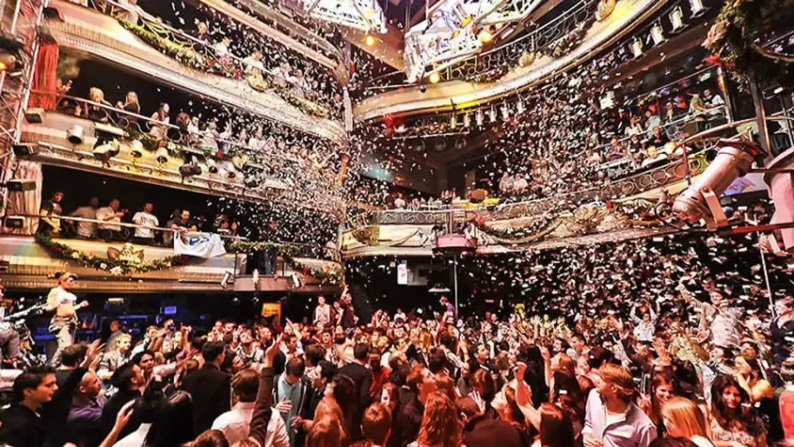 Festa scatenata con coriandoli nella **discoteca Kapital di Madrid**. La folla esulta su più livelli, immersa in un'atmosfera di gioia e divertimento.