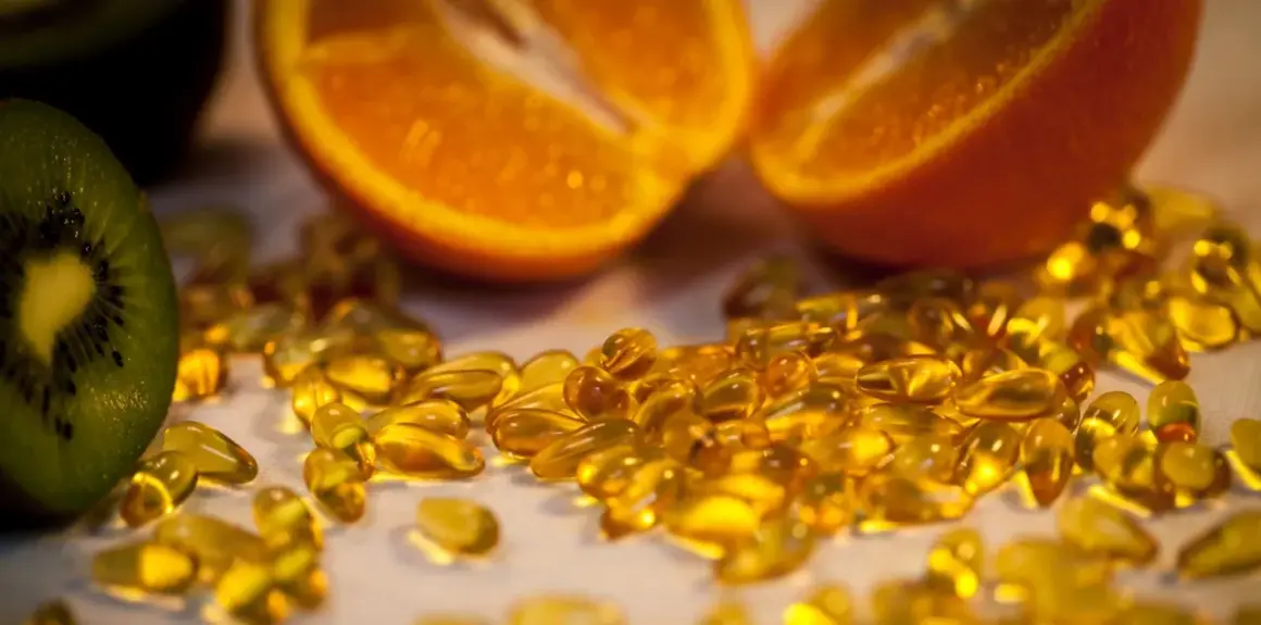 Orangenscheiben und Kiwi neben vielen gelben Kapseln. Die Wirkung von hochdosiertem Vitamin C für die Gesundheit.