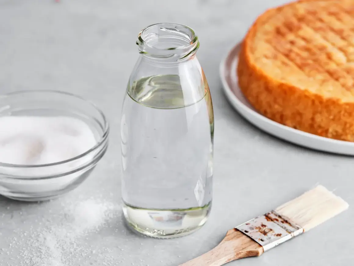 Zutaten für zuckersirup selber machen: Zucker, Wasser in Flasche, Pinsel und ein Kuchenboden.