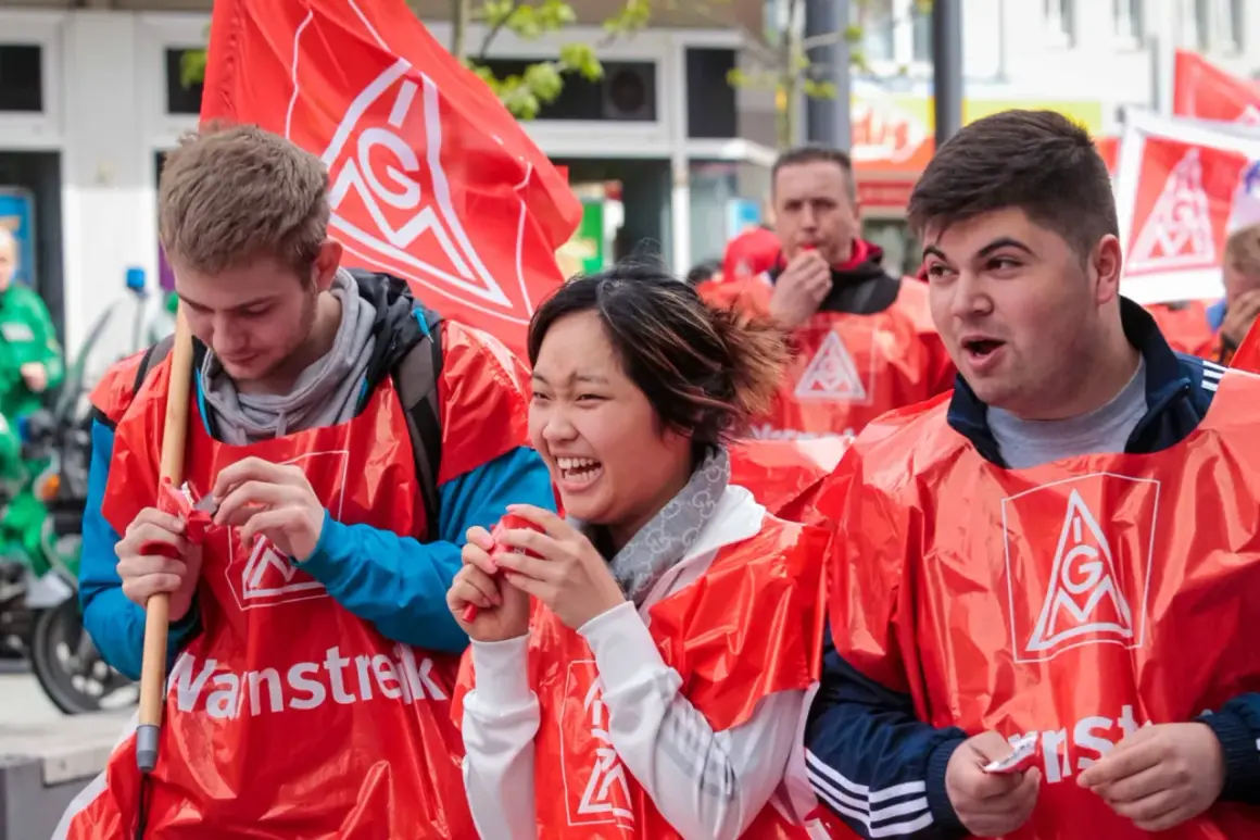 Junge Leute in roten Westen mit IG Metall Logo bei einer Demonstration. Sie wirken engagiert und hoffnungsvoll für die jav Wahlen.
