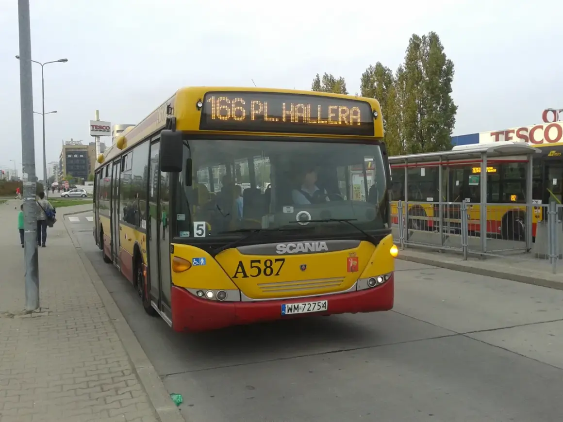 Żółty autobus linii 166 w Warszawie, z napisem "166 PL. HALLERA" na wyświetlaczu, stoi na przystanku obok centrum handlowego Tesco.
